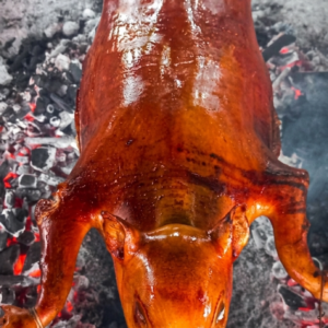 A whole Lechon Cochinillo (suckling pig) roasting to a golden-brown, crispy finish.